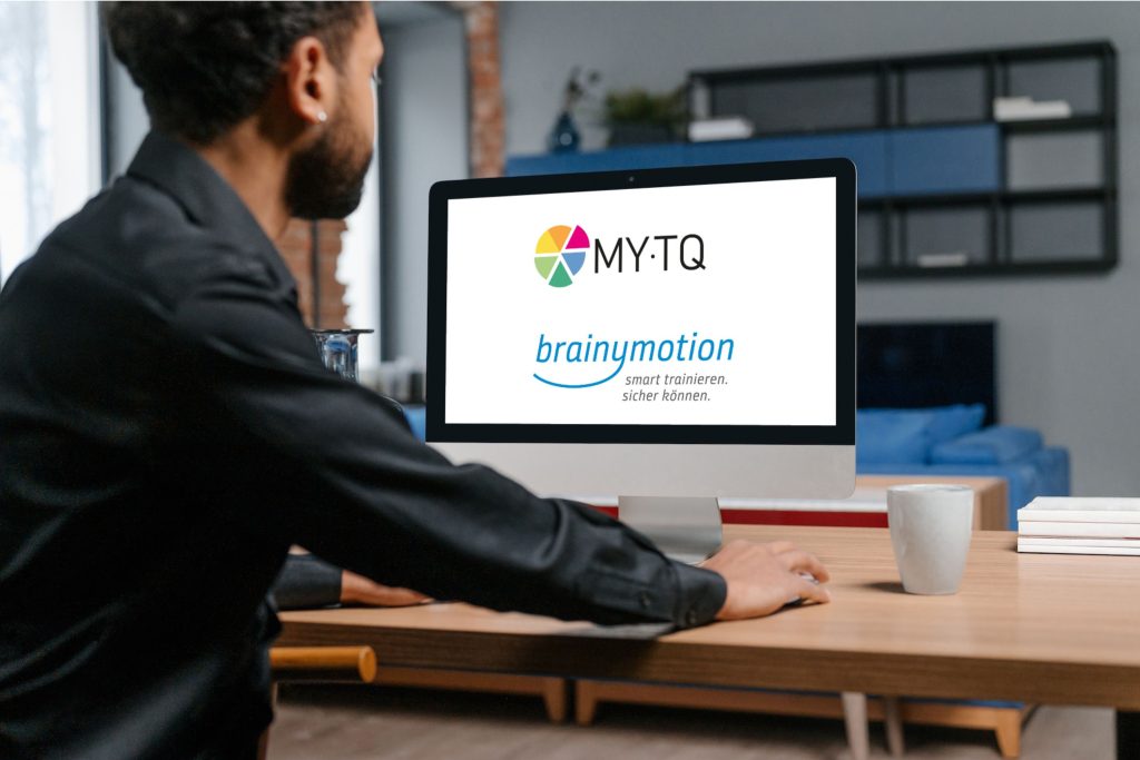 Mann sitz vor PC mit MYTQ Logo auf dem PC